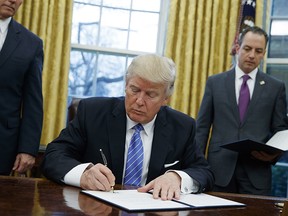 In this Monday, Jan. 23, 2017, file photo, President Donald Trump signs an executive order to withdraw the U.S. from the 12-nation Trans-Pacific Partnership trade pact agreed to under the Obama administration in the Oval Office of the White House in Washington.