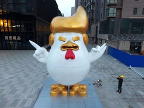 A worker takes a picture of a giant rooster sculpture resembling U.S. President-elect Donald Trump on display outside a shopping mall to celebrate the upcoming Chinese Year of the Rooster in Taiyuan in north China's Shanxi province, Thursday Dec. 29, 2016. Trump has vowed to label China a currency manipulator on his first day in the White House