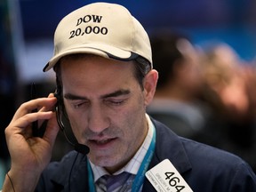 A trader wears a 'Dow 20,000' hat works on the floor of the New York Stock Exchange.
