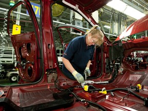 A worker installs parts into the interior of a GMC Terrain vehicle at the CAMI Automotive Inc. plant assembly line in Ingersoll, Ontario.