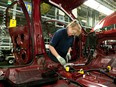 A worker installs parts into the interior of a GMC Terrain vehicle at the CAMI Automotive Inc. plant assembly line in Ingersoll, Ontario.