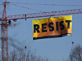 Greenpeace activists hang from a construction crane with a banner that reads "Resist"