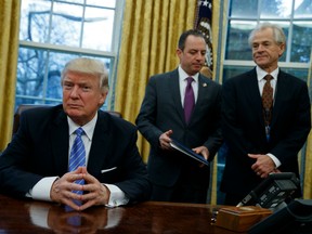 National Trade Council adviser Peter Navarro, right, and White House Chief of Staff Reince Priebus, center, await President Donald Trump's signing three executive orders
