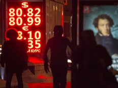People walk past an exchange office screen showing the currency exchange rates of the Russian ruble, U.S. dollar and euro, in Moscow, Russia, Wednesday, Jan. 20, 2016.