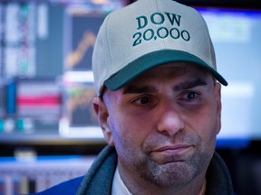 A trader wearing a "DOW 20,000" hat works on the floor of the New York Stock Exchange.