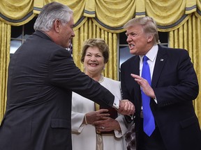 U.S. President Donald Trump (R) shakes hands with Rex Tillerson (L) as Tillerson's wife Renda St. Clair look on after Tillerson was sworn in as Secretary of State in the Oval Office