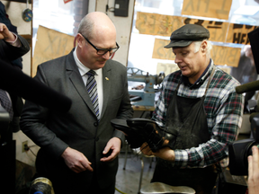 Finance Minister Michael de Jong picks up his newly-soled shoes in advance of the provincial budget in Victoria, B.C.