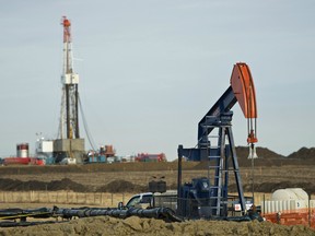 Pumpjack works in the foreground with a drilling rig on a Husky Oil site east of Bruderheim, Alberta.