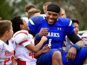 NFL player Cam Newton, right, bumping fists with youth football player Keilan Matthews, 8,  during the filming of a Buick commercial for this year's Super Bowl.