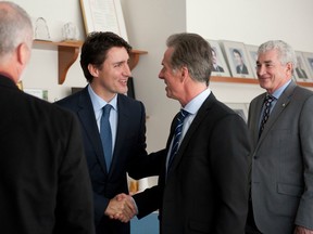 Prime Minister Justin Trudeau greets Don Walker, left, CEO of Magna International, at a roundtable discussion with members of the Automotive Parts Manufacturers' Association.