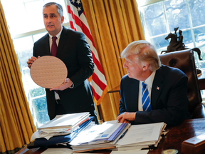 President Donald Trump looks at Intel CEO Brian Krzanich, holding a silicon wafer, during their meeting in the Oval Office of the White House.