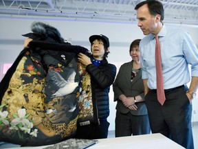 Eric Chan, left, faculty at the Applied Research and Innovation Centre at Algonquin College, shows Minister of Finance Bill Morneau a jacket featuring his original art that he collaborated on with Canada Goose.