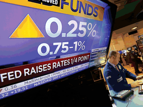 Specialist Edward Loggie works at his post as a television screen on the floor of the New York Stock Exchange shows the decision of the Federal Reserve, Wednesday. The Fed's key short-term rate is rising by a quarter-point to a still-low range of 0.75 percent to 1 per cent.