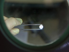 An employee uses a magnifying lens and tweezers to inspect a Torasemid AL high blood pressure tablet at the Stada Arzneimittel AG pharmaceutical factory in Bad Vilbel, Germany, on Wednesday, April 9, 2014.