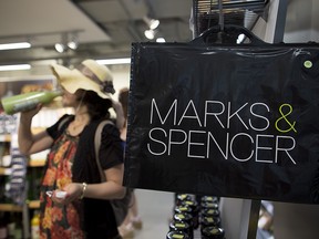 A Marks & Spencer Group Plc. shopping bag hangs inside the company's food store in Hong Kong, China, on Friday, June 13, 2014.