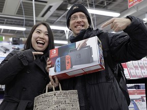 A customer poses with a box of Nintendo Switch after purchasing one on launch day