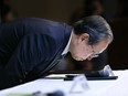 Toshiba Corp. President Satoshi Tsunakawa leans over a table as he takes a seat upon his arrival for a press conference at the company's headquarters in Tokyo, Wednesday, March 29, 2017.