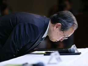 Toshiba Corp. President Satoshi Tsunakawa leans over a table as he takes a seat upon his arrival for a press conference at the company's headquarters in Tokyo, Wednesday, March 29, 2017.