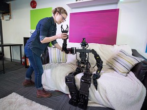 Engineer Olivia Norton positions Thormang, a full-scale humanoid robot used for research, on a couch at the Vancouver office of artificial intelligence company Kindred AI.