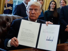 President Donald Trump shows his signature on an executive order