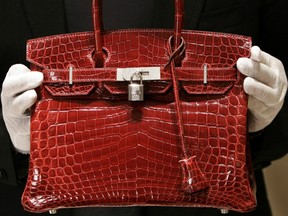 A file photo taken in New York 21 June 2007 shows an employee holding a 129,000 USD crocodile-skin Hermes "Birkin" bag.