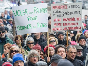 Protesters hold up signs during a demonstration outside Bombardier's head office in Montreal on Sunday, to protest recent pay hikes and bonuses to the company's top executives.