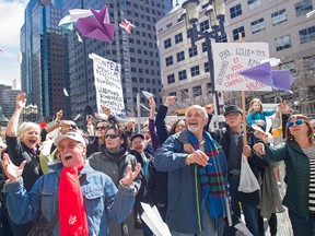 People throw paper airplanes during a demonstration outside Quebec Premier Philippe Couillard's office in Montreal, Sunday, April 9, 2017, to protest recent pay hikes and bonuses to Bombardier's top executives.