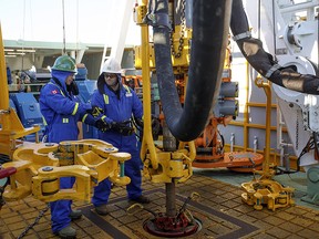 Trainee Kyle Robinson, left, talks with instructor Clint Dyck train to lay down drill pipe on a rig floor at Precision Drilling in Nisku, Alta., on Friday, January 20, 2016.