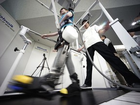 A model demonstrates the Welwalk WW-1000, a wearable robotic leg brace designed to help partially paralyzed people walk at the main system with treadmill and monitor,  at Toyota Motor Corp.'s head office in Tokyo, Wednesday, April 12, 2017.