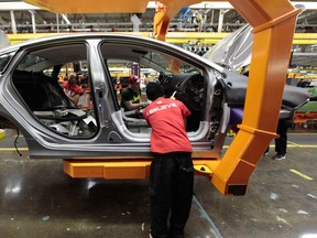 Assembly line workers build a car at an assembly plant in Michigan.