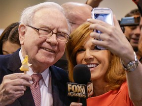 Berkshire Hathaway Chairman and CEO Warren Buffett, holds an ice cream bar as he poses for a selfie with Liz Claman of the Fox Business Network, as he tours the exhibit floor at the CenturyLink Center in Omaha, Neb., at the annual Berkshire Hathaway shareholders meeting.