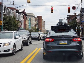 A self-driving Uber car stops at a red light on Liberty Avenue through the Bloomfield neighborhood of Pittsburgh.