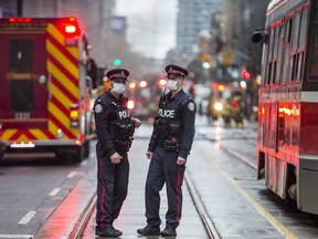 Police wear masks as thick smoke fills the air after the explosion underground on King St. W., west of Yonge St. in downtown Toronto, Ont. on Monday May 1.