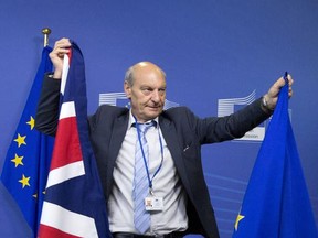 A member of protocol changes the EU and British flags prior to the arrival of EU Chief Brexit Negotiator Michel Barnier and British Secretary of State David Davis at EU headquarters in Brussels on Monday, June 19, 2017. Brexit negotiators will discuss Monday Britain's financial obligations to the European Union as the long, complicated and potentially perilous process of the U.K. leaving the bloc finally gets underway. (AP Photo/Virginia Mayo)