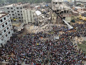 FILE - In this April 25, 2013, file photo, Bangladeshi people gather as rescuers search for survivors and victims after the Rana Plaza building collapsed which housed five garment factories in Savar, near Dhaka, Bangladesh.  Leading global fashion brands and trade unions announced a three year agreement in Paris, France, Thursday June 29, 2017, to continue a safety program for fire and building safety involving thousands of garment factories in Bangladesh. (AP Photo/A.M.Ahad, File)