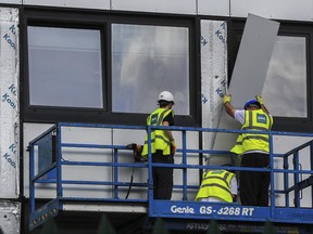 Workers remove cladding from Whitebeam Court, in Pendleton, Manchester, Monday June 26, 2017. The list of high-rise apartment towers in Britain that have failed fire safety tests grew to 60, officials said Sunday, revealing the mounting challenge the government faces in the aftermath of London's Grenfell Tower fire tragedy. (Peter Byrne/PA via AP)