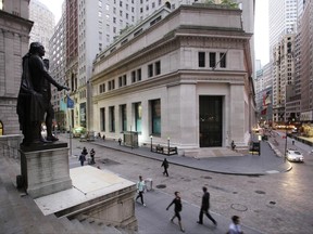 FILE - In this Oct. 8, 2014, file photo, people walk to work on Wall Street beneath a statue of George Washington, in New York. Technology companies and banks are leading stock indexes modestly higher in early trading on Wall Street, Monday, June 19, 2017. Apple, Google's parent company, Alphabet, and Bank of America all rose. (AP Photo/Mark Lennihan, File)