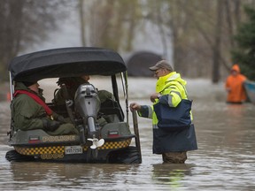 A resident speaks with Quebec provincial police after checking out his home in Rigaud, Quebec in the May floods.