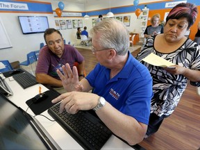 FILE - In this Tuesday, Oct. 1, 2013, file photo, Alan Leafman, center, president of Health Insurance Express, Inc., helps Raquel Bernal, right, and her husband John Bernal, both of Apache Junction, Ariz., navigate the nation's health care insurance system online at the Health Insurance Express store in Mesa, Ariz. Enough insurers are planning to sell coverage through the Affordable Care Act in 2018 to keep the market place working, if only barely, in most parts of the country. However competition in many markets has dwindled to one insurer, or none in some cases, and another round of steep price hikes is expected to squeeze consumers who don't receive big income-based tax credits to help pay their bill. (AP Photo/Ross D. Franklin, File)