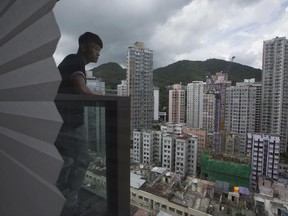 In this June 10, 2017 photo, Donny Chan stands on the balcony at his apartment, one of a growing number of tiny, upscale units known as "microflats" in Hong Kong. Hong Kong's property developers are scaling down, way down, for younger, middle-class buyers, offering micro-sized upscale apartments with stratospheric price tags. The apartments, dubbed "mosquito-size units" or "gnat flats" in Chinese are drawing online ridicule and underscore worries over the Asian financial hub's overheated real estate market and widening inequality. (AP Photo/Kin Cheung)