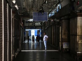 A man stands outside closed shops during a strike against implementation of the nationwide Goods and Services Tax (GST) in Kolkata, India, Friday, June 30, 2017. The new GST regime will replace a complicated mix of state and federal and will impact the final price of nearly everything an average consumer purchases. (AP Photo/Bikas Das)