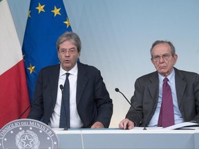 Italian Prime Minister Paolo Gentiloni, left, and Italian Economy Minister Pier Carlo Padoan, give a press conference after a cabinet meeting at Chigi Palace in Rome, Italy, Sunday, June 25, 2017. The Italian government is making 5.2 billion euros ($5.8 billion) of resources available to keep operative two banks that the European Central Bank last week had deemed "failing or about to fail," sending them into insolvency procedures. (Claudio Peri/ANSA via AP)