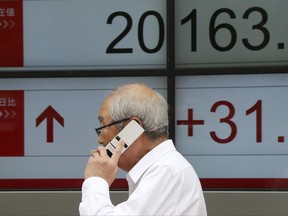 A man walks in front of an electronic stock board of a securities firm in Tokyo, Monday, June 26, 2017.  Asian markets rose Monday after Wall Street rebounded from losses to end the week higher on stronger oil and natural gas prices. (AP Photo/Koji Sasahara)