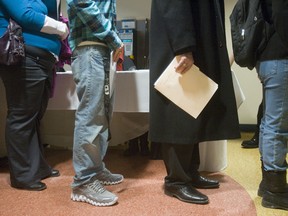 Resumes in hand, people line up for a job fair.