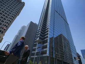 People walk by the newly build Wilshire Grand Center in Los Angeles on Thursday, June 22, 2017. The 73-story, 1,100-foot-high (335.3 meters) Wilshire Grand Center, the tallest building west of the Mississippi, opens Friday, celebrating with lights and fanfare in a once-stodgy downtown that has erupted in new skyscrapers. (AP Photo/Richard Vogel)