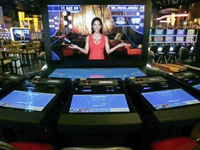FILE - In this June 23, 2015, file photograph, an automated dealer asks for players to take a seat at a black jack video slot machine on the floor of the Plainridge Park Casino in Plainville, Mass. The state's only casino generated about $157 million in gross gambling revenues since June 2016, slightly higher than the $154 million it registered in its first full year but still far short of the $300 million initially projected for the slots parlor and harness racing track when it opened. (AP Photo/Charles Krupa, File)