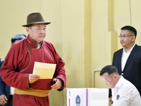 Speaker of Parliament and Mongolian People's Party presidential candidate Miyegombo Enkhbold, left, casts his vote at a polling station at a school in Ulaanbaatar, Mongolia, Monday, June 26, 2017. Mongolians are voting for a new president on Monday in a race pitting a horse salesman against a former judo star and a nationalist wanting to get more from the vast landlocked country's mineral wealth. (AP Photo/Chadraabal Baramsai)