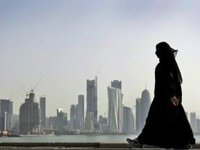 A Qatari woman walks in front of the city skyline in Doha. Saudi Arabia and three Arab countries have severed ties to Qatar.