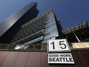 FILE - In this June 2, 2014, file photo, a sign that reads "15 Good Work Seattle" is displayed below Seattle City Hall, right, and the Columbia Center building, left, after the Seattle City Council passed a $15 minimum wage measure. A new study says Seattle's $15-an-hour minimum wage law has boosted pay for restaurant industry workers without costing jobs. The report, from the University of California at Berkeley, is certain to add to the debate as activists around the country push for increases in local, state and federal minimum wages. (AP Photo/Ted S. Warren, File)