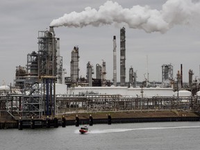A boat passes a refinery standing along the Houston Ship Channel in Houston, Texas, U.S.,